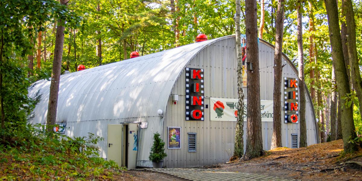 Wald halbrundes Kinogebäude Plakate Bäume 