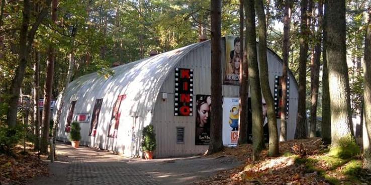 Wald halbrundes Kinogebäude Plakate Bäume 