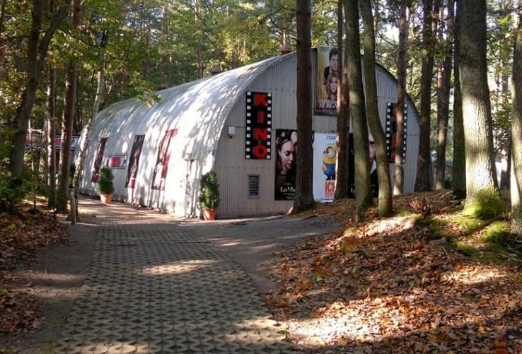 Wald halbrundes Kinogebäude Plakate Bäume 